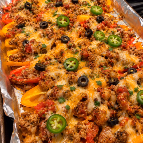Mini bell pepper turkey nachos topped with melted cheese, black olives, jalapeño, and Greek yogurt.